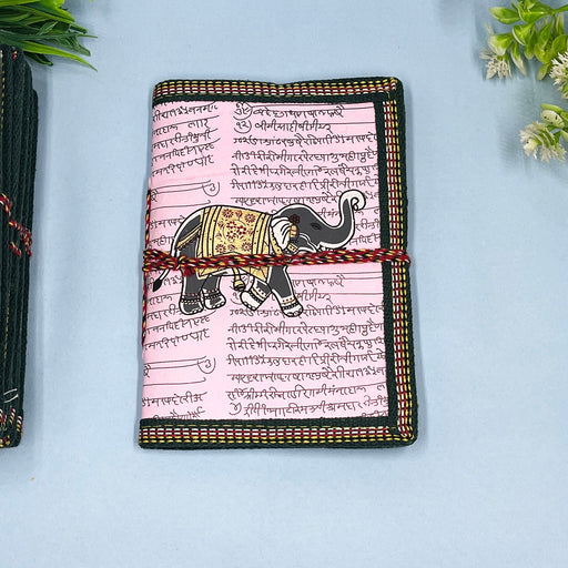 A handmade cotton paper diary with elephant print, bound with a red and black string, placed on a blue surface.