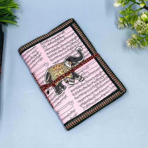 A handmade cotton paper diary with elephant print, bound with a red and black string, placed on a blue surface.