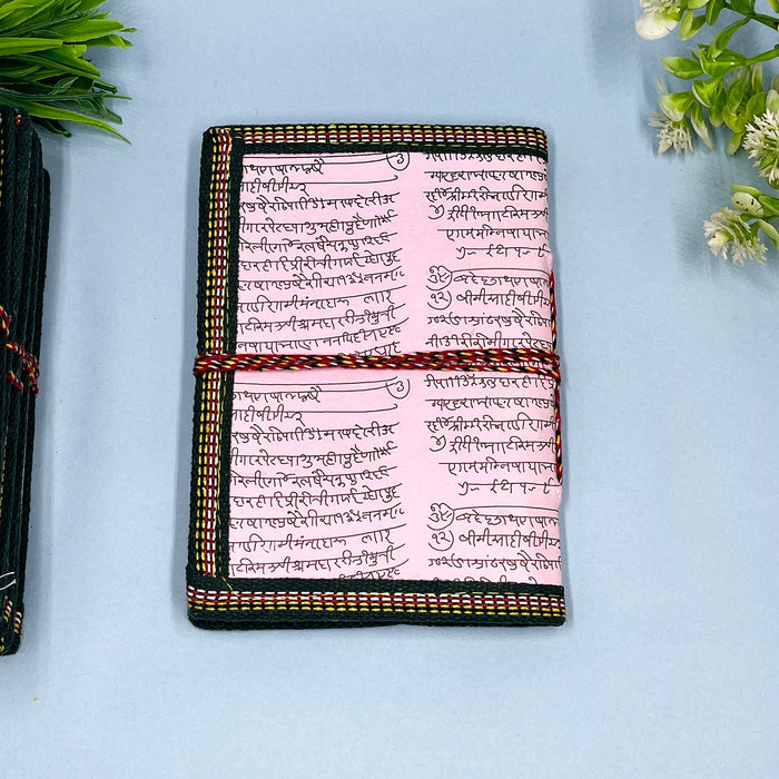 A handmade cotton paper diary with elephant print, bound with a red and black string, placed on a blue surface.