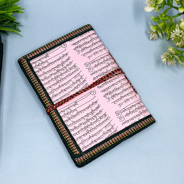 A handmade cotton paper diary with elephant print, bound with a red and black string, placed on a blue surface.