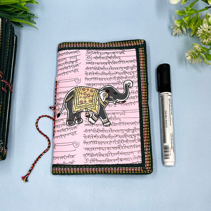 A handmade cotton paper diary with elephant print, bound with a red and black string, placed on a blue surface.