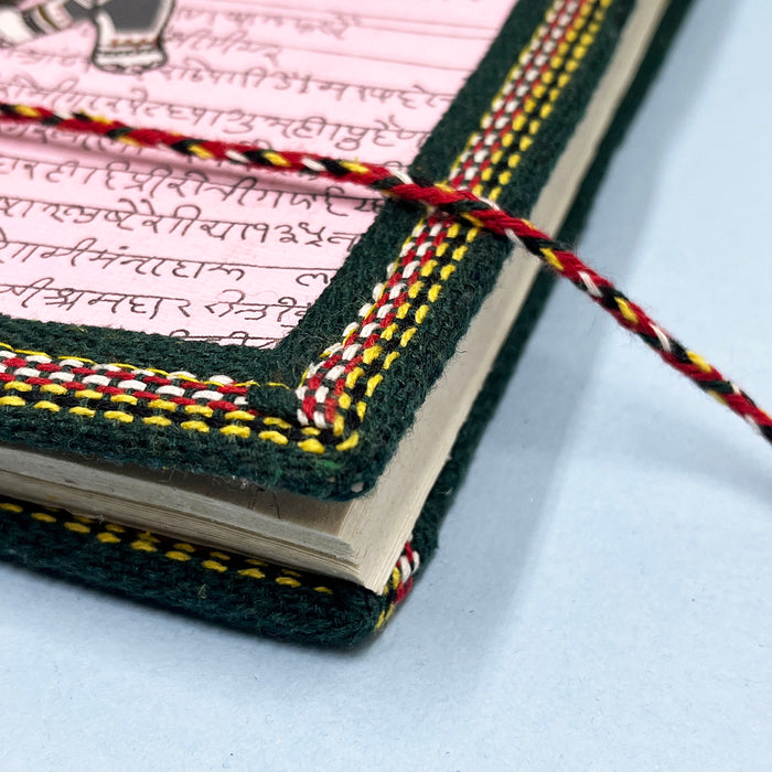 A handmade cotton paper diary with elephant print, bound with a red and black string, placed on a blue surface.